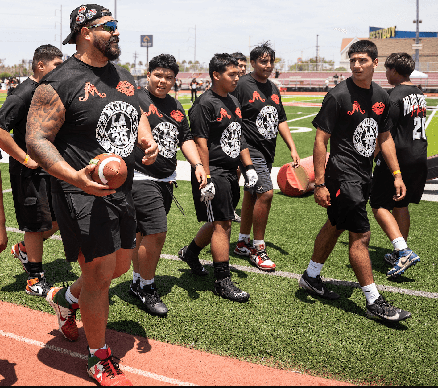 Will Hernandez leading a group of young athletes in Mijos Foundation gear across a football field